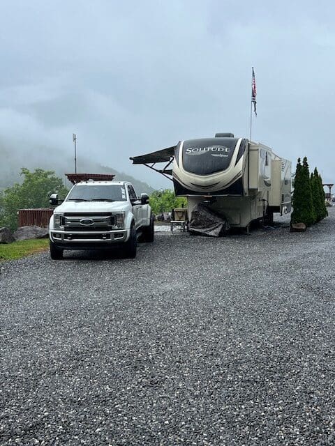 A truck and trailer are parked on the gravel.