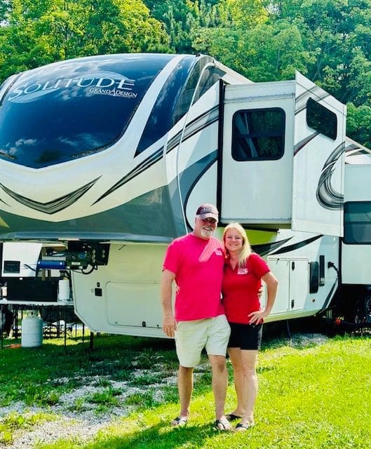 A man and woman standing in front of an rv.