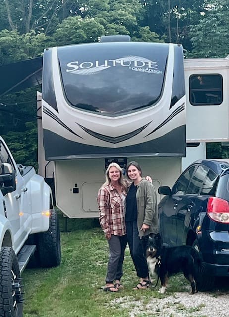 Two women standing in front of a camper.