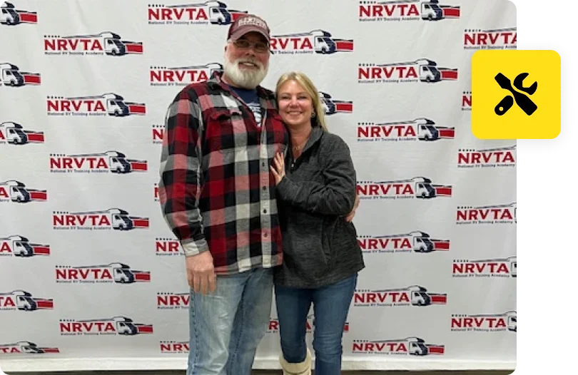 A man and woman posing for the camera in front of a nrvta sign.